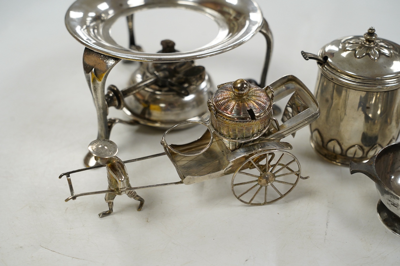 Five assorted silver condiments, including Chinese white metal modelled a rickshaw, together with a plated tea kettle stand with burner. Condition - poor to fair